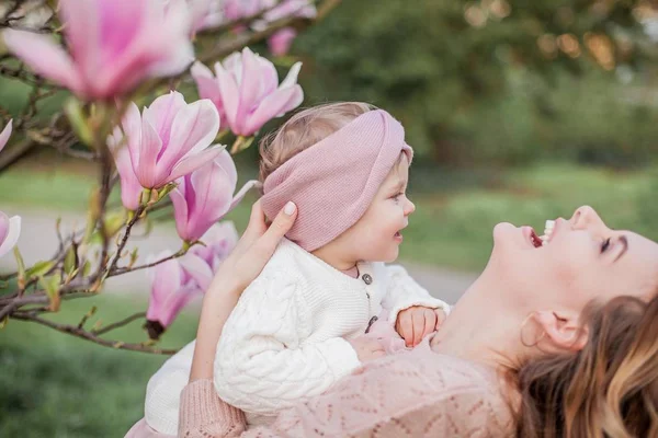 Mooie jonge moeder en kleine dochter in de buurt van de Magnolia. Lente familieportret. — Stockfoto