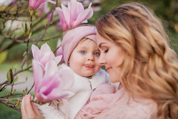 Hermosa joven madre e hija pequeña cerca de la magnolia. Retrato familiar de primavera . —  Fotos de Stock