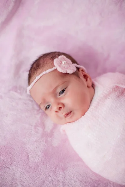 Kleine pasgeboren baby in een roze pak op een roze achtergrond. Moederschap. — Stockfoto