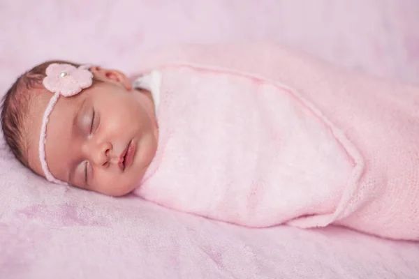 Lilla nyfödda barnet i en rosa kostym på en rosa bakgrund. Moderskap. — Stockfoto