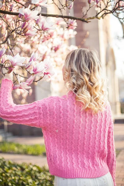 Portret van een mooie jonge vrouw in de buurt van een magnolia. Lente. — Stockfoto