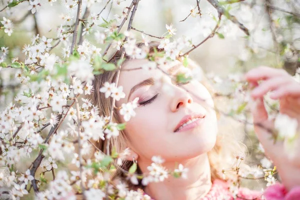 Retrato de primavera de uma jovem loira perto de uma árvore florida. Jovem feliz . — Fotografia de Stock