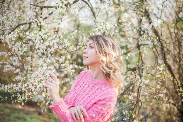 Jarní portrét mladé blondýny nedaleko kvetoucího stromu. Šťastná mladá žena. — Stock fotografie