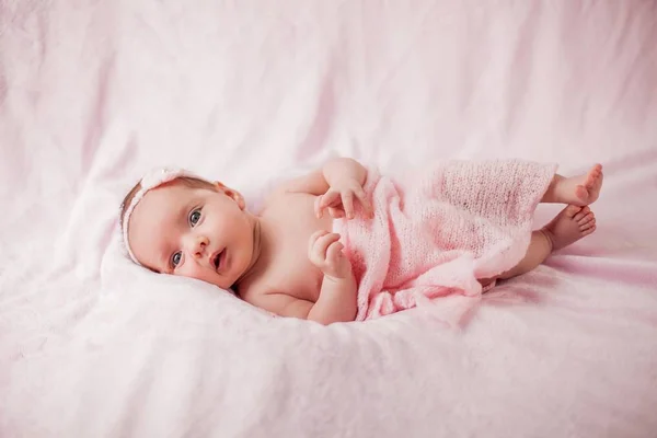 Kleine pasgeboren baby in een roze pak op een roze achtergrond. Moederschap. — Stockfoto