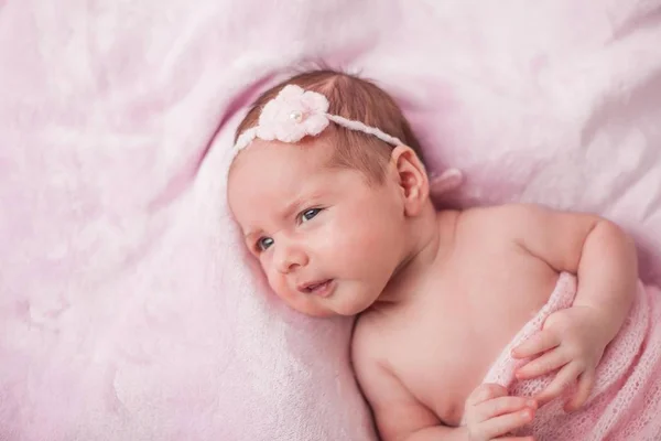 Lilla nyfödda barnet i en rosa kostym på en rosa bakgrund. Moderskap. — Stockfoto
