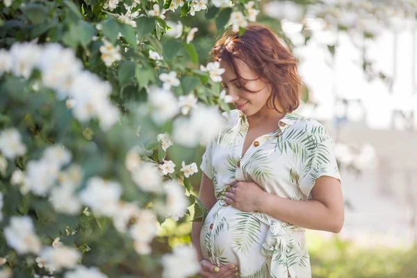 Wanita muda cantik yang bahagia sedang berdiri di dekat pohon yang sedang bermekaran. Keibuan. Cinta. Spring . — Stok Foto