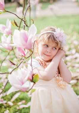 Küçük sevimli sarışın kız 3 yaşında bir çiçek manolya yakın bir parkta oynar.