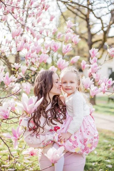 Красива молода мати і маленька донька біля квітучої магнолії. Весна. Рожевий цвіте . — стокове фото