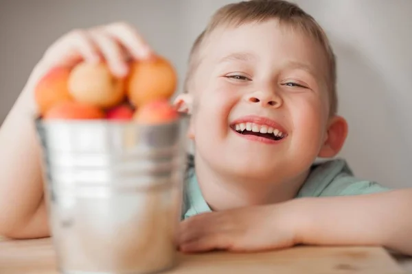 4歳の小さなかわいい男の子がバケツからジューシーなアプリコットを食べています. — ストック写真