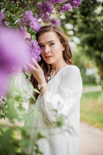 Retrato de una hermosa joven cerca de la floreciente lila. Primavera . — Foto de Stock