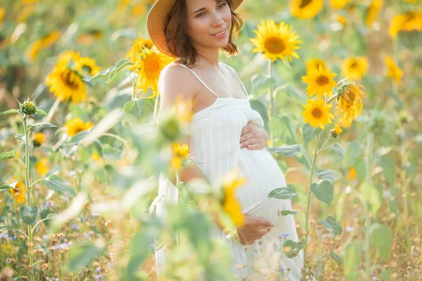 Beautiful young pregnant woman in the sunflower field. Portrait of a young pregnant woman in the sun. Summer. — Stock Photo, Image