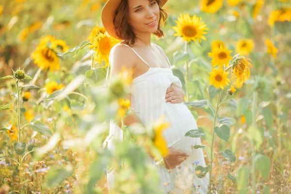 Beautiful young pregnant woman in the sunflower field. Portrait of a young pregnant woman in the sun. Summer. — Stock Photo, Image
