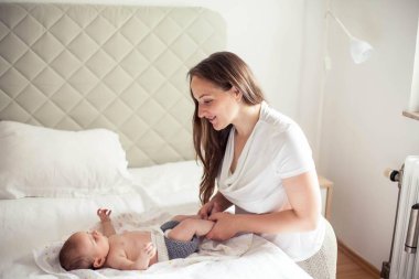 Genç ve güzel bir anne bir bebek doğuruyor. Anne bebeğe yatakta masaj yapıyor..