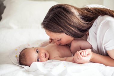 Genç ve güzel bir anne bir bebek doğuruyor. Annem bebeğini öper. Çocuk yatak odası.