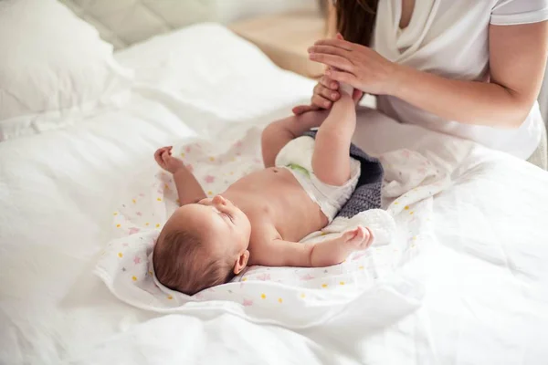 Genç ve güzel bir anne bir bebek doğuruyor. Anne bebeğe yatakta masaj yapıyor.. — Stok fotoğraf