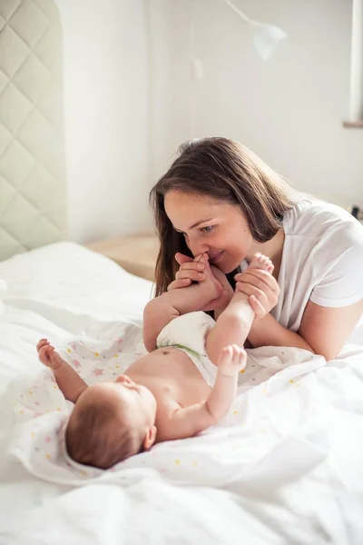 Genç ve güzel bir anne bir bebek doğuruyor. Annem bebeğini öper. Çocuk yatak odası. — Stok fotoğraf