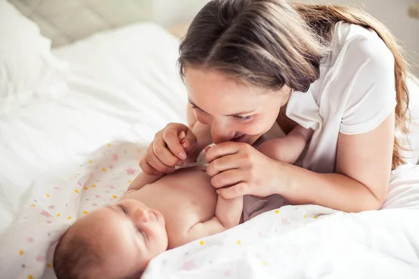 Genç ve güzel bir anne bir bebek doğuruyor. Annem bebeğini öper. Çocuk yatak odası. — Stok fotoğraf