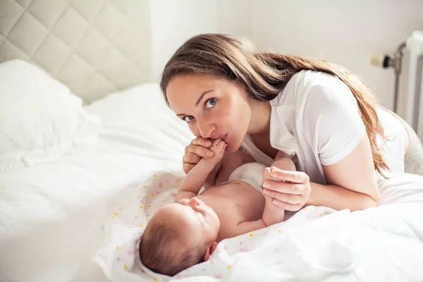 Mladá krásná matka drží dítě. Máma líbá své dítě. Dětské ložnice. — Stock fotografie