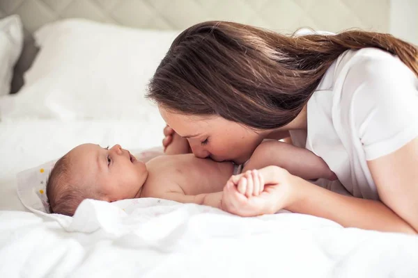 Tânăra mamă frumoasă ţine un copil. Mama îşi sărută copilul. Dormitor pentru copii . — Fotografie, imagine de stoc