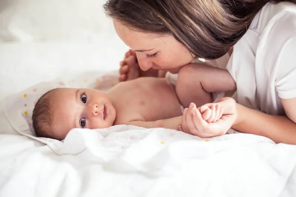 Joven hermosa madre sostiene a un bebé. Mamá besa a su bebé. Dormitorio para niños . — Foto de Stock