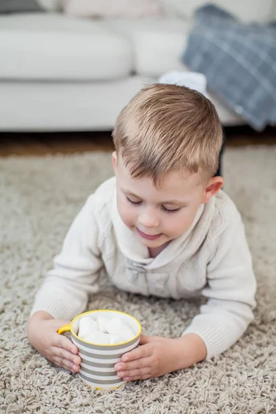 Bir rahat sonbahar portre tatlı bir çocuk. 4 yaşında küçük bir çocuk bir halı üzerinde oturur ve kakao içiyor. Sonbahar.
