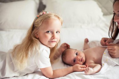 Genç ve güzel bir anne bir bebek doğuruyor. Küçük kız kardeşi küçük kız kardeşini öper. Bebek. Çocuk yatak odası.