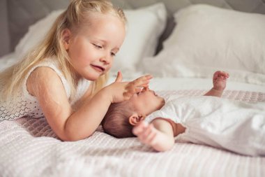 Genç ve güzel bir anne bir bebek doğuruyor. Küçük kız kardeşi küçük kız kardeşini öper. Bebek. Çocuk yatak odası.