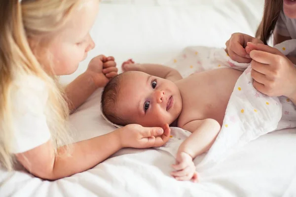 Junge schöne Mutter hält ein Baby. Kleine Schwester küsst ihre kleine Schwester. Baby. Kinderzimmer. — Stockfoto