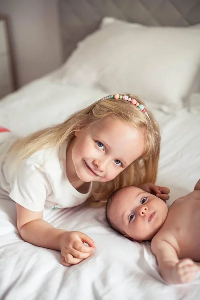 Mladá krásná matka drží dítě. Malá sestřička líbá svou malou sestru. Dítě. Dětská ložnice. — Stock fotografie