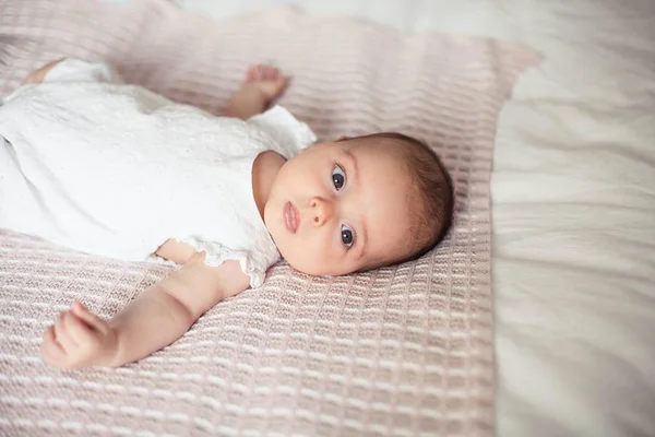 Ένα μικρό χαριτωμένο κορίτσι 3 μηνών είναι ξαπλωμένο στο κρεβάτι. Μωρό. Παιδικό υπνοδωμάτιο. — Φωτογραφία Αρχείου