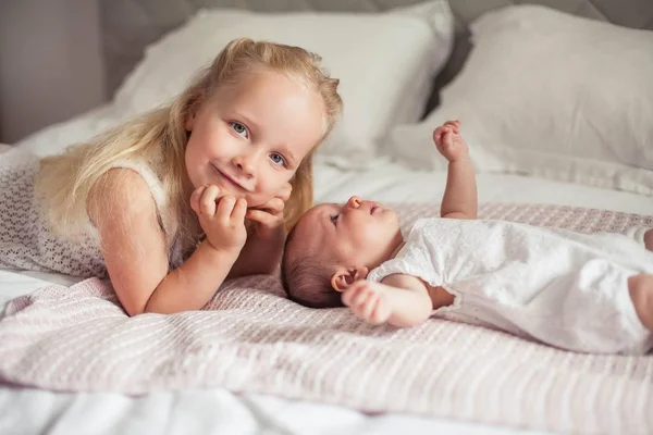 Mladá krásná matka drží dítě. Malá sestřička líbá svou malou sestru. Dítě. Dětská ložnice. — Stock fotografie