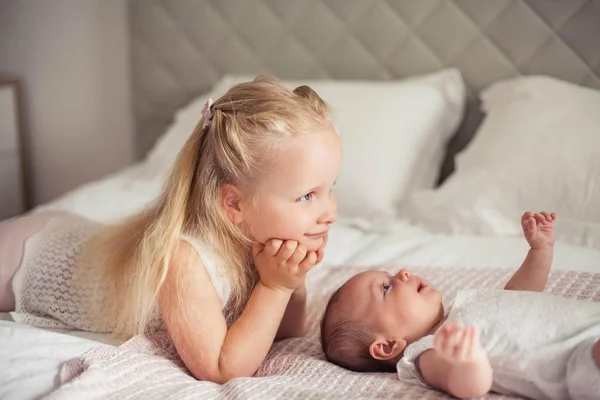 Jovem mãe bonita segura um bebê. A irmãzinha beija a irmãzinha. Querida... Quarto das crianças . — Fotografia de Stock