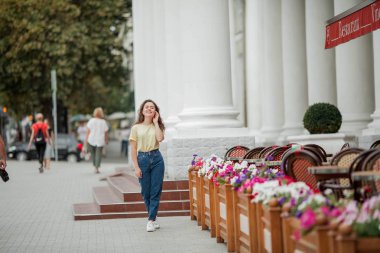 16 yaşında güzel bir genç kadın bir Fransız kafeyakınında duruyor. Turizm. Çiçek. Yaz.
