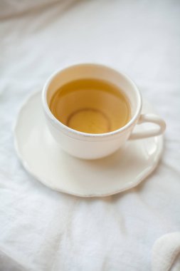Yatakta çay olan beyaz bir fincan. Rahat. Sonbahar. Kış.