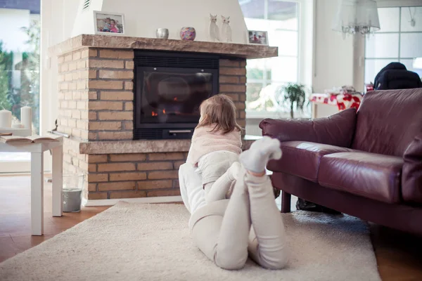 Mooie jonge gezin is het lezen van een boek bij de open haard. Gezellige. — Stockfoto