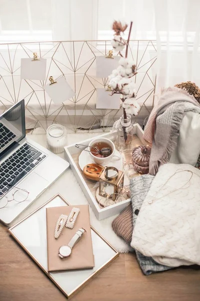 Tonlu fotoğraf. Sonbahar dekoru. Bir laptop, bir kupa sıcak çay, bir çörek, mumlar. Samimi. Sonbahar.