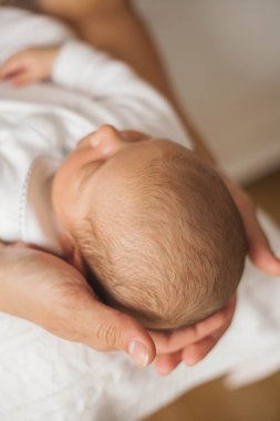 Yakın plan. Yeni doğmuş şirin bebek annesinin kollarında uyuyor. Annelik.