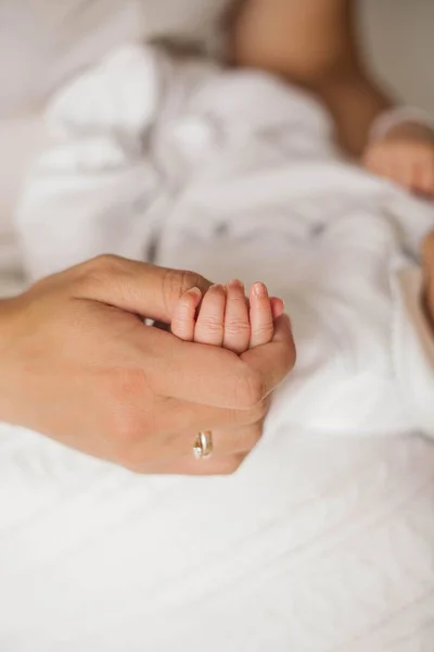 Närbild. Barnets handtag ligger i mammas händer. Söta nyfödda barn sover i mammas armar. Moderskap. — Stockfoto