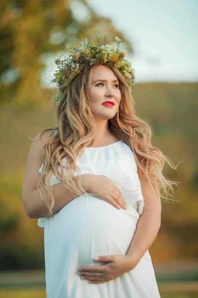태양 속에 임신 한 여성의 사진. 아름다운 임산부 가 전장에서 화관을 머리에 쓰고 있습니다. 엄마가 되는 거지. 따뜻 한 가을. — 스톡 사진
