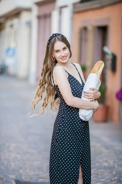 ヨーロッパの街の美しい若い女性はフランスのバゲットを持っています フランス式 — ストック写真