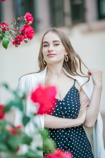 Молодая красивая женщина гуляет по европейскому городу. Портрет молодой женщины возле цветущих роз. Европа . — стоковое фото