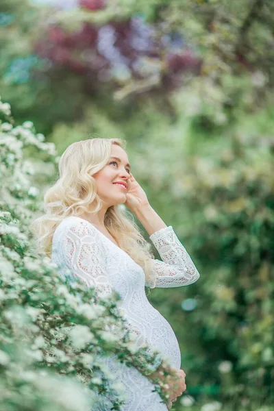 Молодая Красивая Беременная Женщина Кружевном Белом Платье Гуляет Цветущем Парке — стоковое фото
