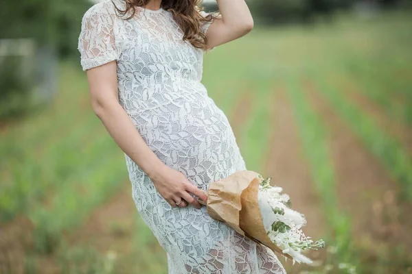 一个年轻漂亮的孕妇的画像 一个带着一束鲜花的孕妇在公园里散步 — 图库照片