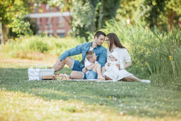 Νεαρή όμορφη οικογένεια τρώει μεσημεριανό δίπλα στη λίμνη. Καλοκαιρινό πικ. — Φωτογραφία Αρχείου