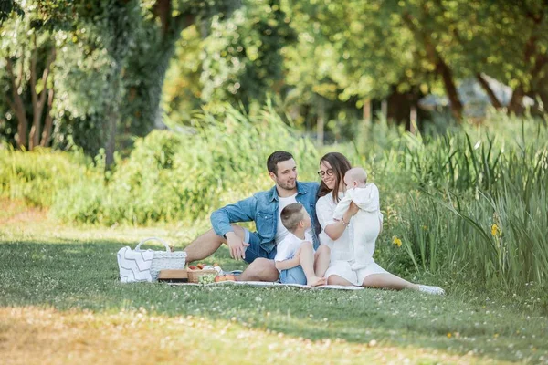 Genç ve güzel bir aile göl kenarında öğle yemeği yiyor. Yaz pikniği. — Stok fotoğraf