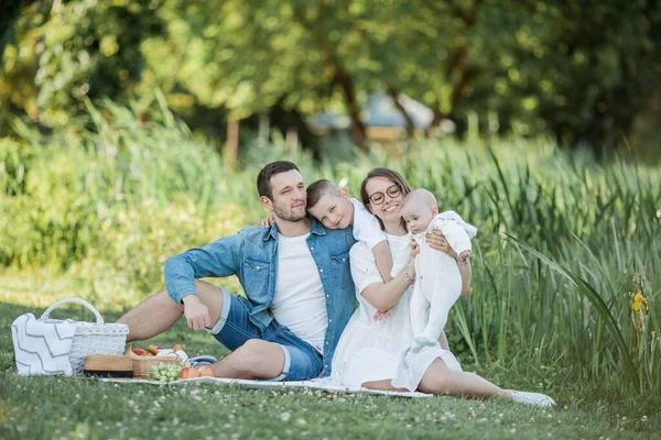 Genç ve güzel bir aile göl kenarında öğle yemeği yiyor. Yaz pikniği. — Stok fotoğraf