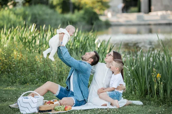 湖で昼食をとっている若い美しい家族。夏のピクニック. — ストック写真