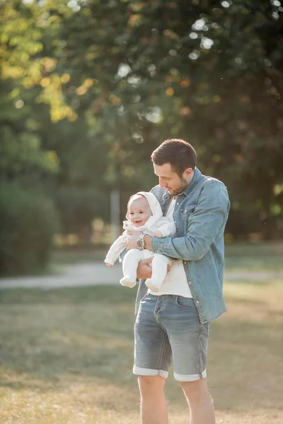 Young beautiful family walks in the park. Family portrait in the sunset light. Summer picnic. Spring.