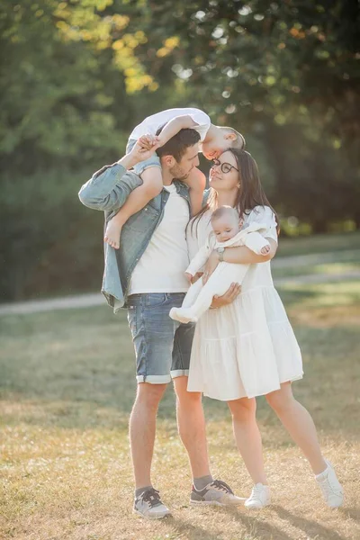 Genç Güzel Bir Aile Parkta Yürüyor Gün Batımında Aile Portresi — Stok fotoğraf