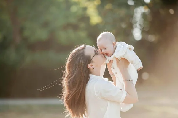 Young beautiful family walks in the park. Family portrait in the sunset light. Summer picnic. — Stock Photo, Image